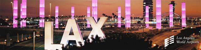 Image of LAX sign in front of pink pillars with blood orange sunset sky, the pillars are pink in honor of Saint Valentines Day.