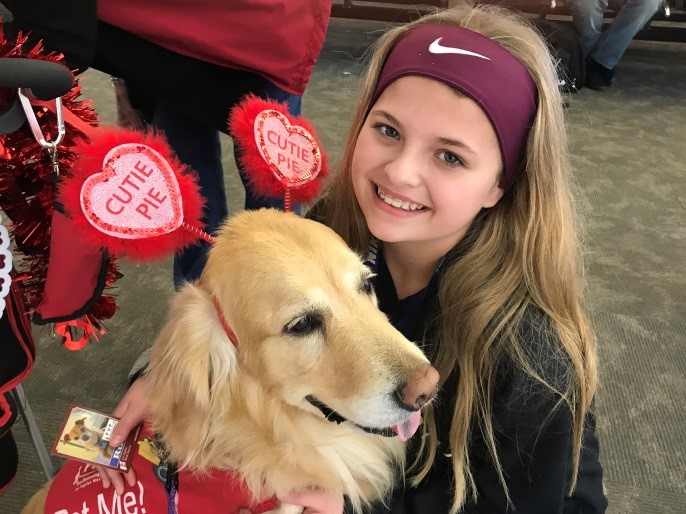 Image of a guest enjoying the company of a golden retriever with cutie pie antennas on.