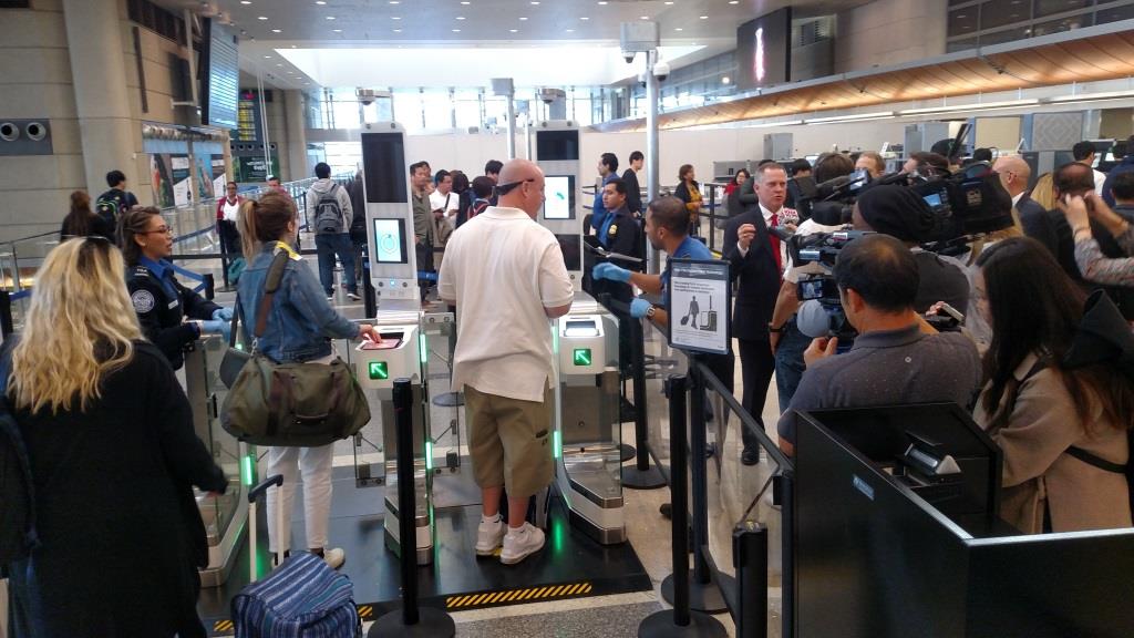 Passengers going through facial recognition E-gates at Tom Bradley International Terminal, a news crew is also there to record the event.